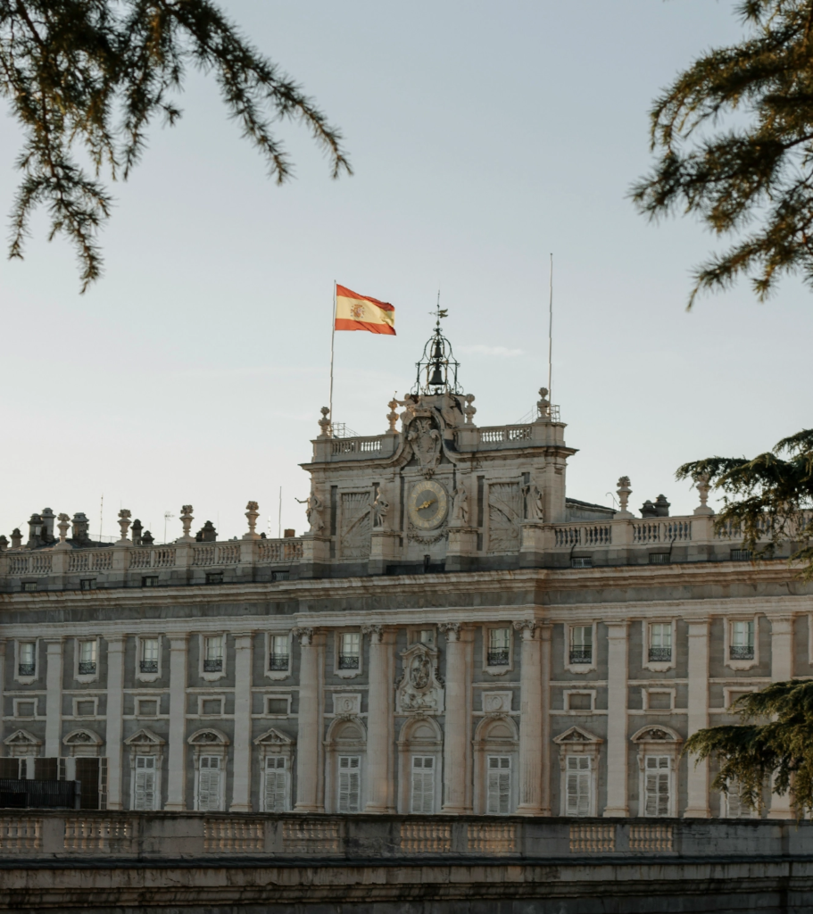 Palacio Real en Madrid con la bandera de España, entorno ideal para estudiantes de MBA de medio tiempo en Madrid.